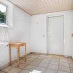 Flur mit Waschbecken, Kleiderhaken und Tür. Holztisch und Schränke sind sichtbar.