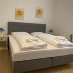 A bedroom with a double bed, two nightstands, and two wall pictures.