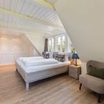 Schlafzimmer mit Dachschräge, Bett, Nachttisch, Sessel und Fenster