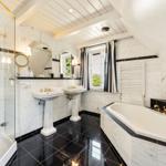Dusche, Badewanne und zwei Waschbecken in einem Badezimmer mit schwarz-weißem Marmor.