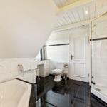 Badezimmer mit Badewanne, Dusche und Toilette unter schrägem Dach