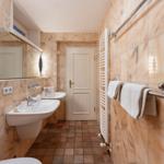 Badezimmer mit Marmortapete, zwei Waschbecken und Handtuchhalter