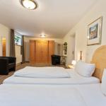 Schlafzimmer mit Doppelbett, Kleiderschrank und Sitzgelegenheit.