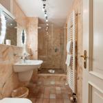 Badezimmer mit Dusche, Waschbecken und Heizkörper an Wand