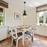 Esszimmer mit Tisch, Stühlen und Fenstern zum Garten.