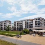 Moderne Ferienwohnung mit Balkon und Außenbereich mit Tischen und Sonnenschirmen.