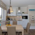 Küche mit Esstisch, Fenster und moderner Einbauküche.
