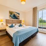Schlafzimmer mit Doppelbett, Balkon und Wandbild.