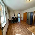 Wohnung mit Essbereich, Küchenzeile und Schlafzimmer. Holzboden und Kühlschrank sichtbar.