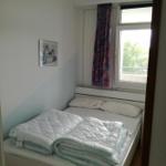 Schlafzimmer mit Doppelbett, Fenster und Vorhang.