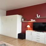 Zimmer mit roter Wand, weißem Schrank und Fernseher auf Kommode.