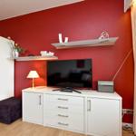 Rotes Wand mit TV-Schrank, Lampe, Regal und Schrank.