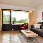 Wohnzimmer mit Sofa, Sitzgelegenheit und Balkonansicht.