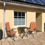 Terrace with two orange chairs and a table. Background: house wall and window.