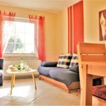 Living area with sofa, table, chairs, and window with red curtains.