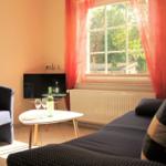 Living room with sofa, armchair, table, TV, and window with red curtains.