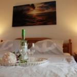 A bed with pillows, a bottle of wine, and two glasses on a tray.