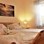 A bed with a wooden frame, a picture on the wall, and a window with curtains.