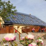 House with solar panels, wooden railings, and flower beds in the garden.