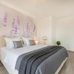 Schlafzimmer mit Bett, Wandbild und Nachttisch.