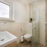 Badezimmer mit Dusche, Toilette und Waschbecken unter Fenster
