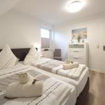 Zimmer mit Doppelbett, Schrank, Fenster und Holzboden.