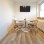 Ein Essbereich mit runden Tisch, zwei Stühlen und Fernseher an der Wand.