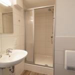 Badezimmer mit Dusche, Waschbecken und Handtuch warmer