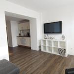 Wohnbereich mit TV, Schrank und Küchenbereich im Hintergrund.