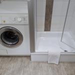 Waschmaschine neben Dusche mit Handtuch