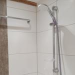 Dusche mit Duschbrause und Handbrause, Wandfliesen und Duschwand