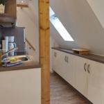 Küche mit Spüle, Kaffeemaschine und Schränken unter Dachschrägen.