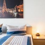 Schlafzimmer mit Bett, Nachttisch und Wandbild eines Platzes