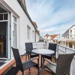 Terrasse mit Tisch und Stühlen, Blick auf Straße und Häuser