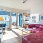 Wohnzimmer mit rotem Sofa, Terrasse und Küchenbereich