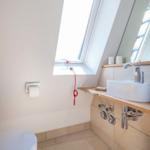 Badezimmer mit Dachfenster, Waschbecken und Toilette.