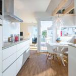 Küche mit Esstisch, Terrasse und Balkon. Moderne Einrichtung mit Holzboden.