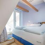 Schlafzimmer mit Dachschrägen, Holzbalken und blau-weißem Bett.