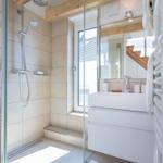 Dusche mit Glaswand, Waschbecken und Fenster