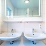 Zwei Waschbecken mit Spiegeln und Heizkörper an der Wand
