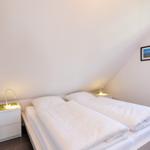 Schlafzimmer mit Doppelbett, zwei Nachttischen und Fenster.