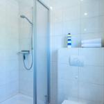 Dusche mit Duschbrause, Handtuch und Leuchtturm-Dekoration