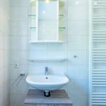 Badezimmer mit Waschbecken, Spiegelschrank und Heizkörper
