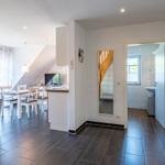Wohnung mit Essbereich, Küche und Bad. Holzboden und Fenster zur Terrasse.