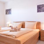 Schlafzimmer mit Holzbett, zwei Nachttischen und Bildern an der Wand.