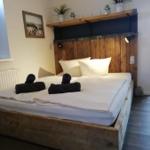 Doppelbett mit Holzgestell, Kopfteil mit Pflanzen und Wandbild.