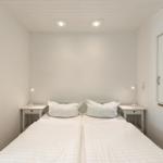 Zimmer mit zwei Betten, Nachttischen und Lampen. Weiße Wände und Decke.