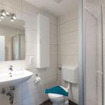 Badezimmer mit Dusche, Toilette und Waschbecken mit Spiegel.