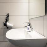 Waschbecken mit Wasserhahn und Haartrockner an der Wand