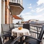 Terrasse mit Tisch und Stühlen, Blick auf Dächer und Himmel.